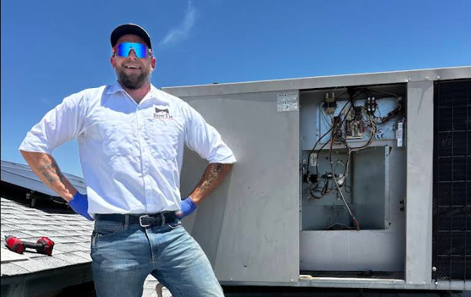 BowTie Home Services technician standing beside an open rooftop HVAC unit in Las Vegas.