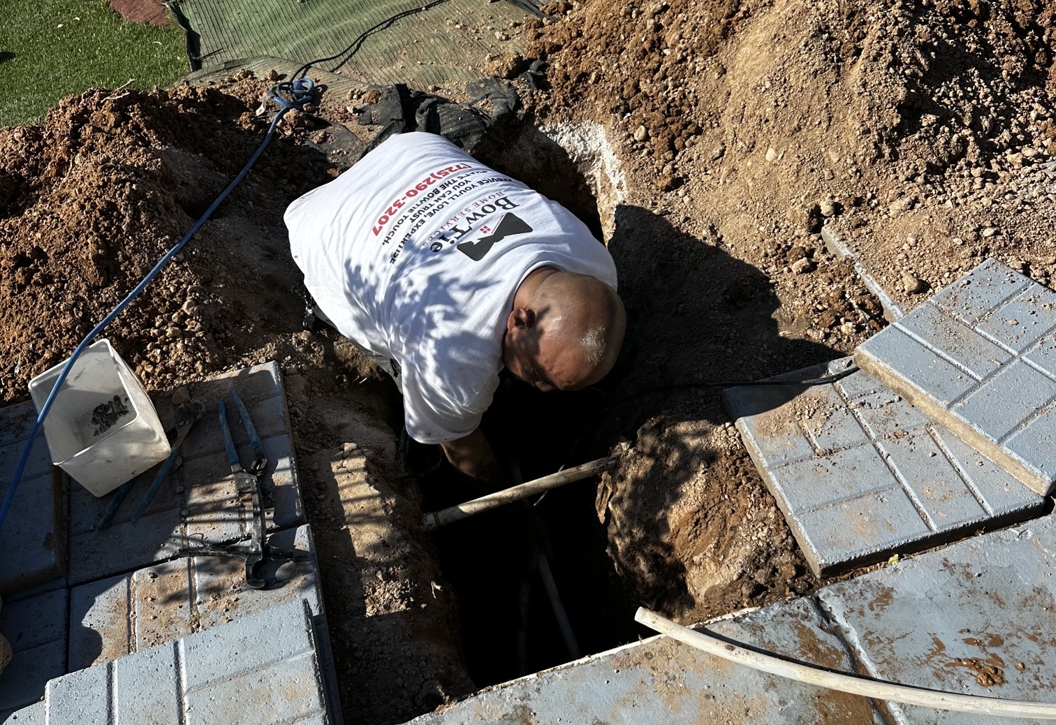 A BowTie Home Services technician works in a trench during a residential plumbing repair in Las Vegas.