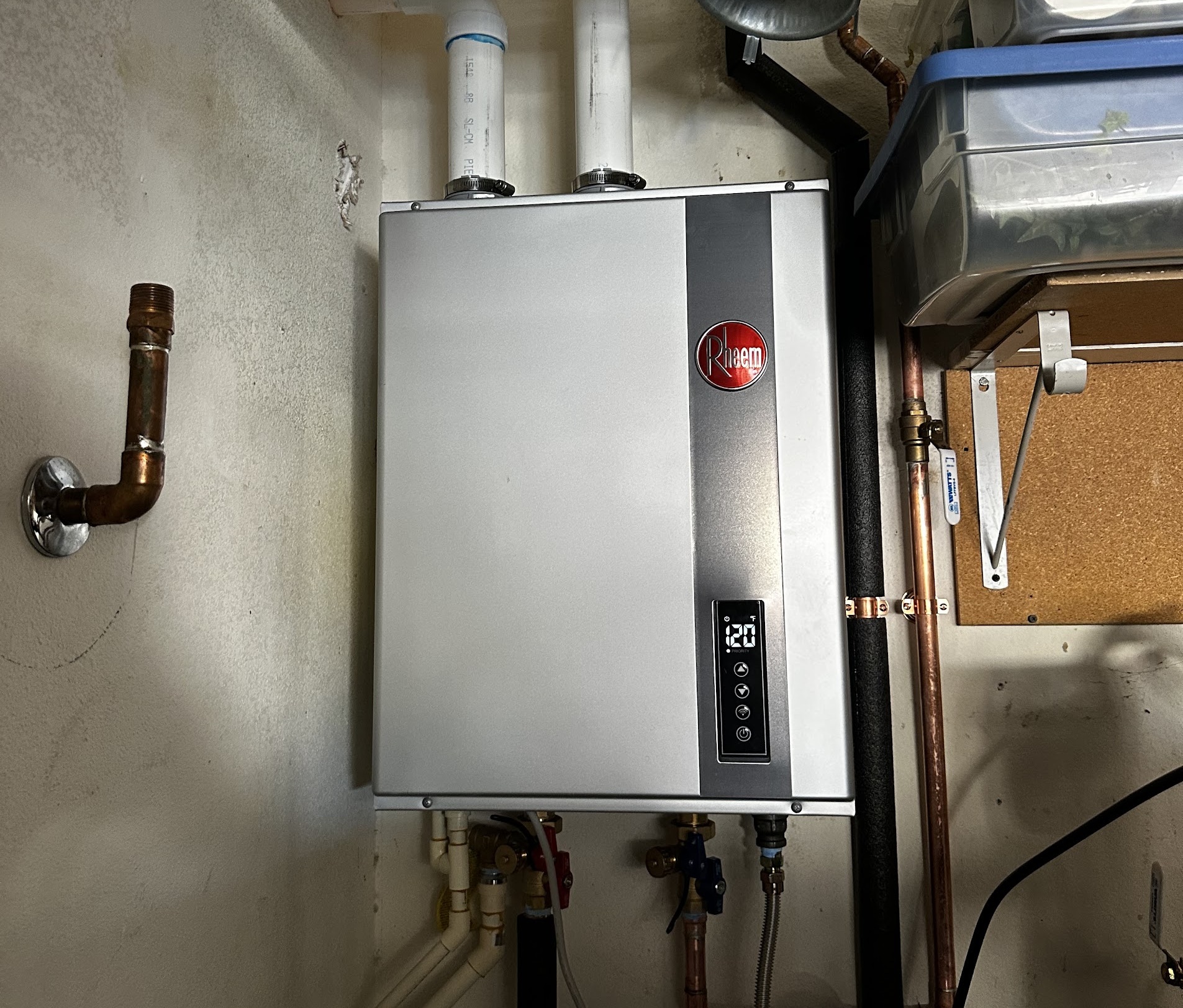 A Rheem tankless water heater mounted on a utility wall with copper and PVC lines in a Las Vegas home.